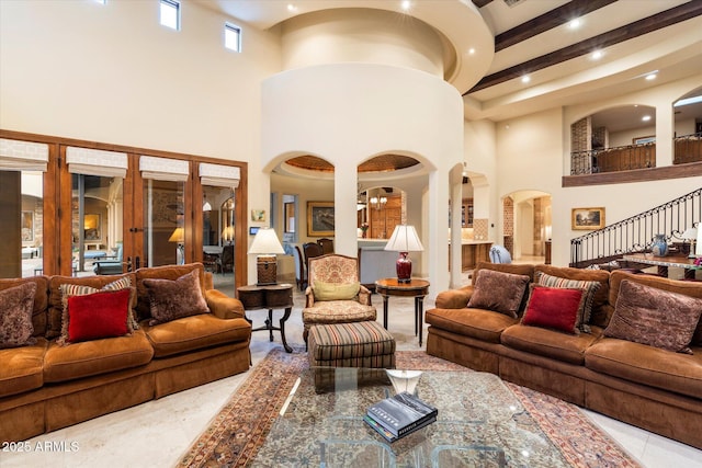 tiled living area with arched walkways, recessed lighting, stairs, and a towering ceiling