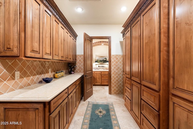 kitchen with brown cabinetry, recessed lighting, light countertops, and wainscoting