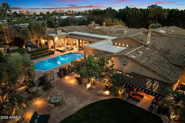 pool at dusk with an outdoor pool and a patio area