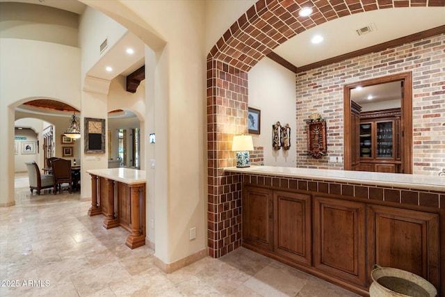 bar with crown molding, visible vents, arched walkways, and baseboards