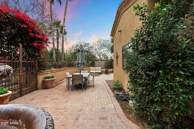 patio terrace at dusk with outdoor dining space, an outdoor hangout area, and fence