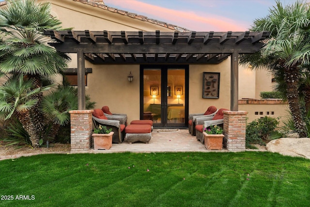 back of property at dusk featuring stucco siding, french doors, a pergola, and a yard