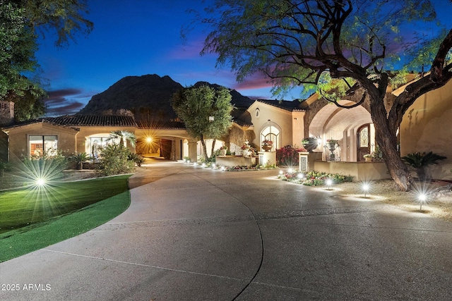 mediterranean / spanish home with stucco siding, a tile roof, and curved driveway