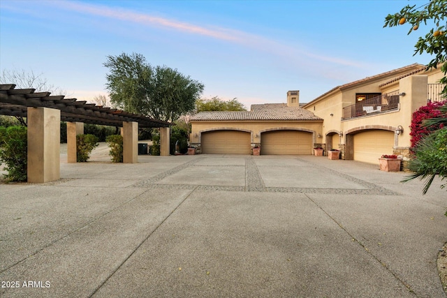 view of front of property featuring a balcony, driveway, a chimney, stucco siding, and a tile roof