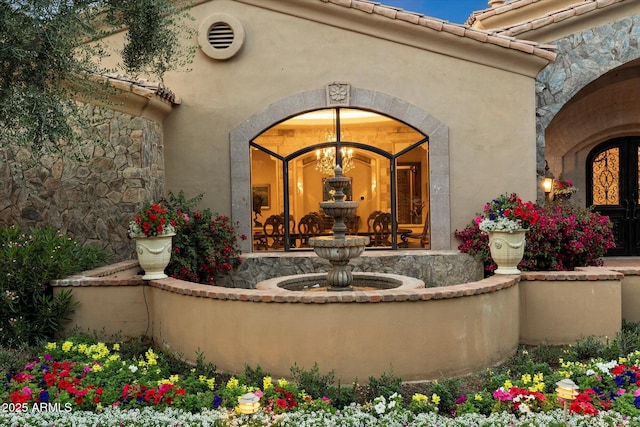 property entrance with a tiled roof, stucco siding, and french doors