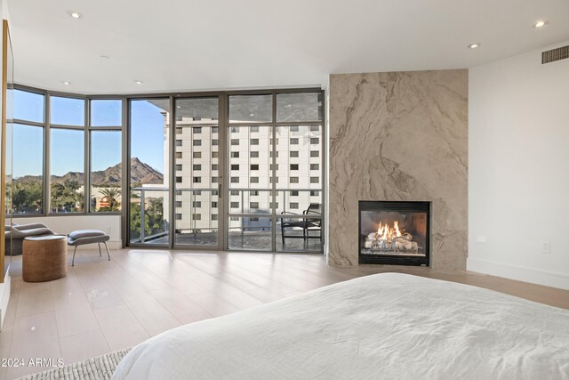 unfurnished bedroom with a large fireplace, baseboards, visible vents, wood finished floors, and recessed lighting