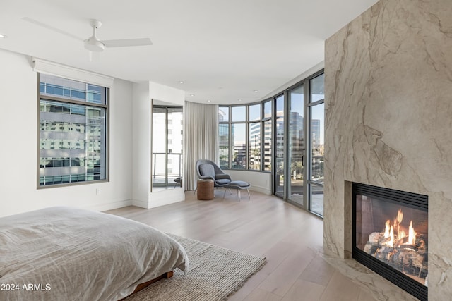 bedroom with light wood-style floors, access to outside, a city view, and a high end fireplace