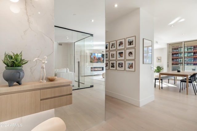 full bathroom with a glass covered fireplace, vanity, wood finished floors, baseboards, and a walk in shower