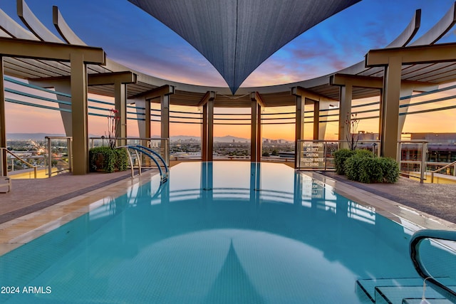 pool at dusk with a patio area and a community pool