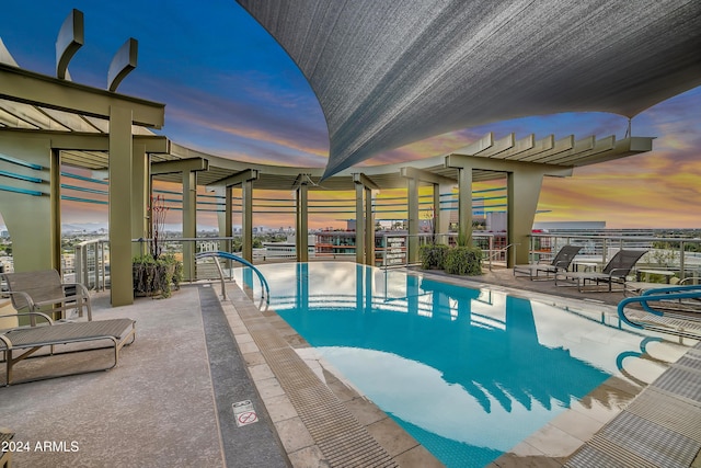 pool at dusk featuring a patio area and a community pool