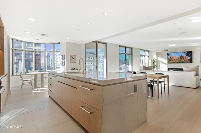 kitchen with a spacious island, light brown cabinetry, open floor plan, a sink, and modern cabinets