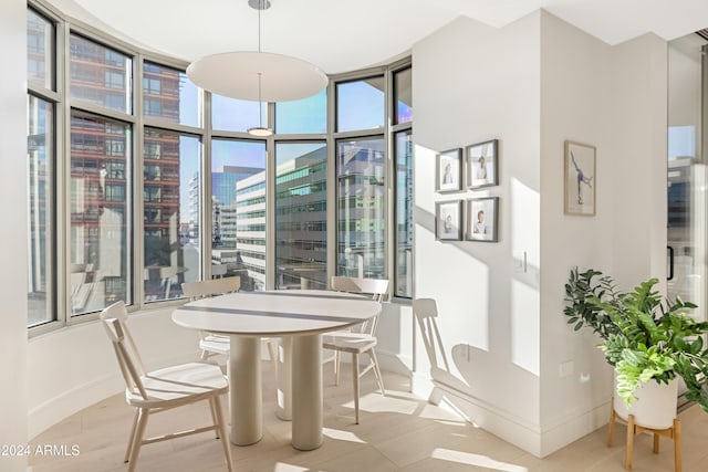 dining area with expansive windows, a city view, and baseboards