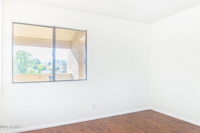 spare room featuring baseboards and wood finished floors