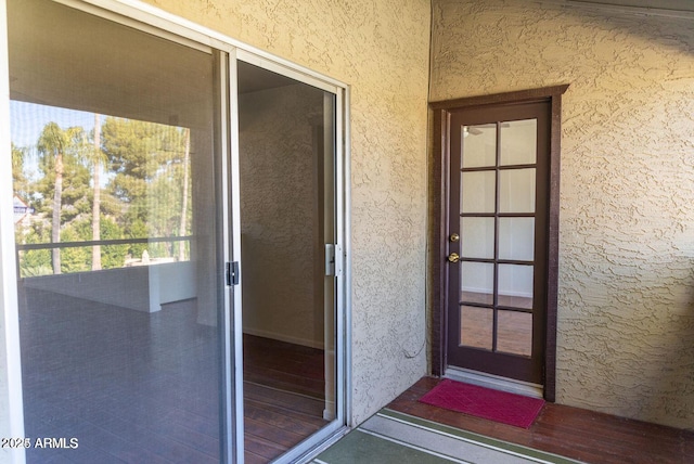 property entrance with stucco siding and a balcony