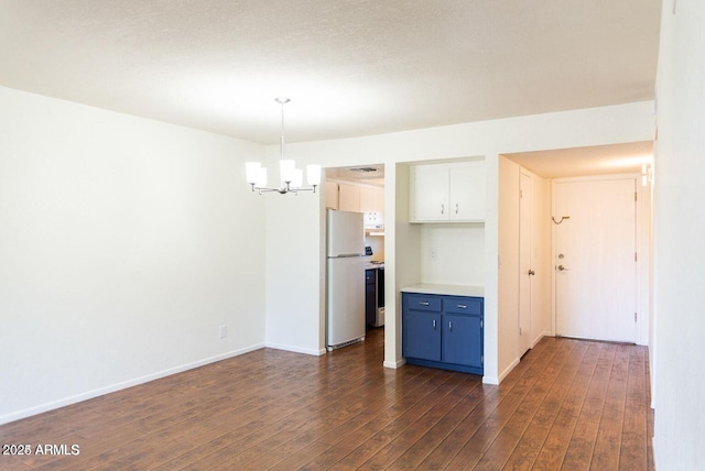 unfurnished dining area with an inviting chandelier, dark wood finished floors, and baseboards