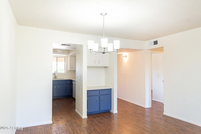 interior space with blue cabinets, a notable chandelier, visible vents, and dark wood finished floors