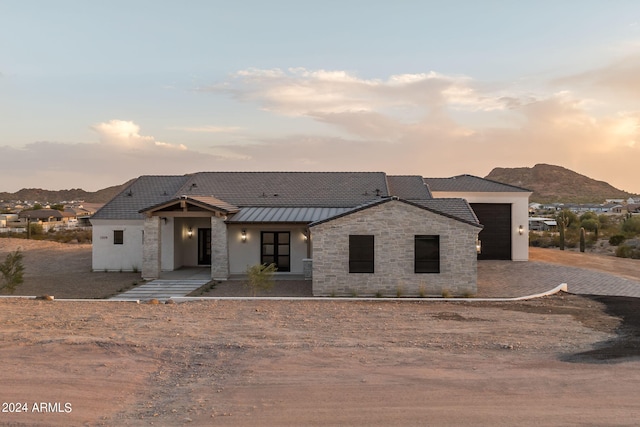 view of front of house with a standing seam roof, stucco siding, stone siding, a mountain view, and metal roof