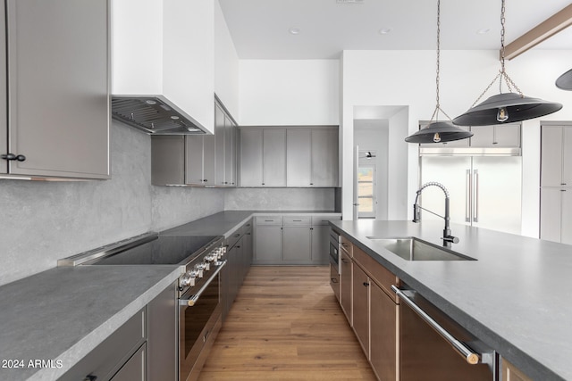 kitchen featuring premium range hood, premium appliances, decorative light fixtures, gray cabinets, and light hardwood / wood-style floors