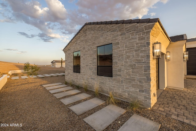 view of side of home featuring stone siding and stucco siding