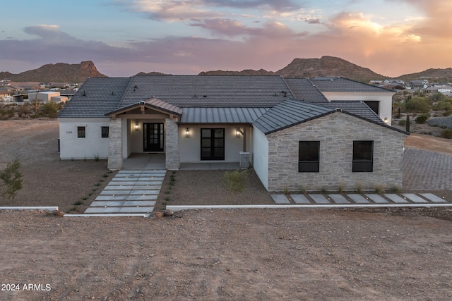 view of front of home featuring a mountain view, stone siding, metal roof, and a standing seam roof