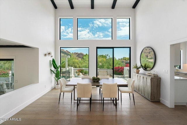 dining room with high vaulted ceiling, beam ceiling, and hardwood / wood-style flooring