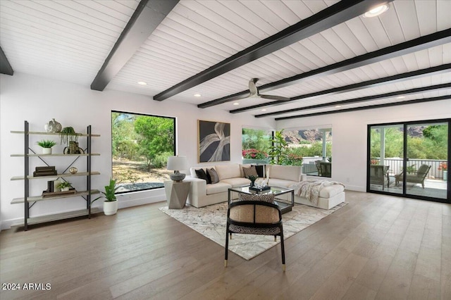 living room with a healthy amount of sunlight, beamed ceiling, and hardwood / wood-style flooring