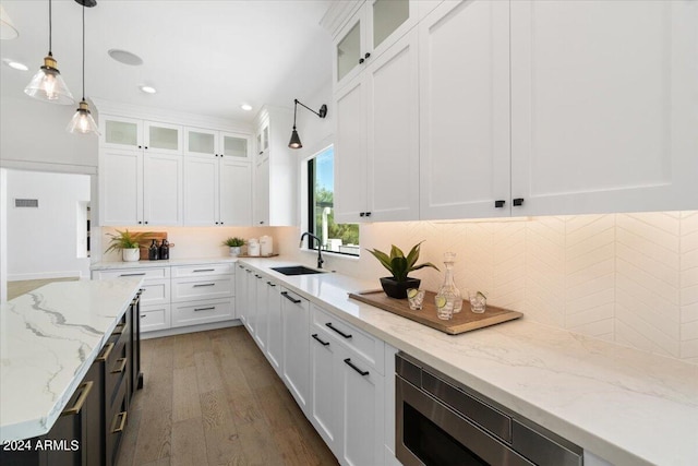 kitchen featuring hardwood / wood-style flooring, tasteful backsplash, white cabinets, sink, and pendant lighting