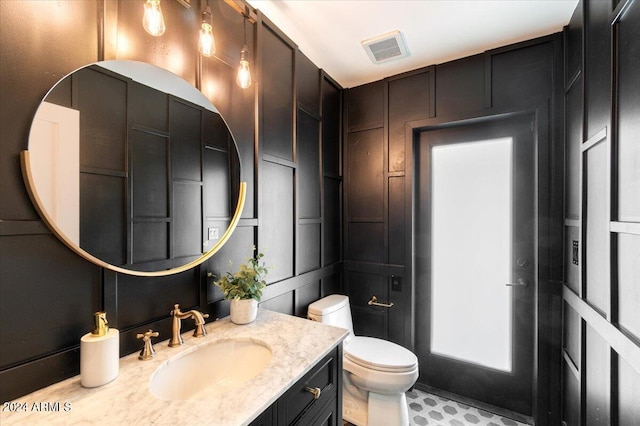 bathroom featuring tile flooring, vanity, and toilet