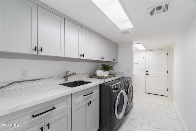 washroom featuring independent washer and dryer, sink, cabinets, and light tile floors