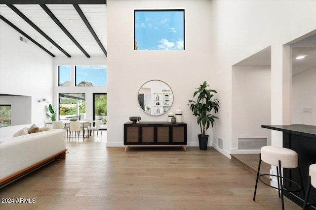 interior space with beamed ceiling, high vaulted ceiling, and hardwood / wood-style floors