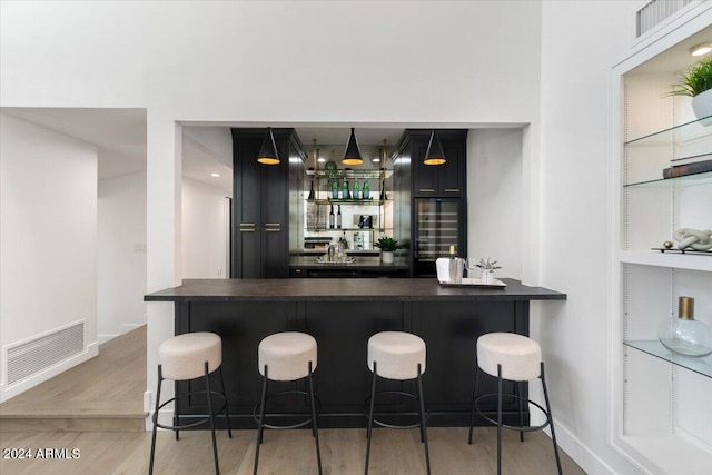 bar with hanging light fixtures and wood-type flooring