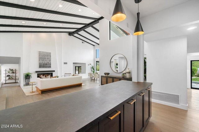 kitchen featuring beam ceiling, high vaulted ceiling, light wood-type flooring, and pendant lighting