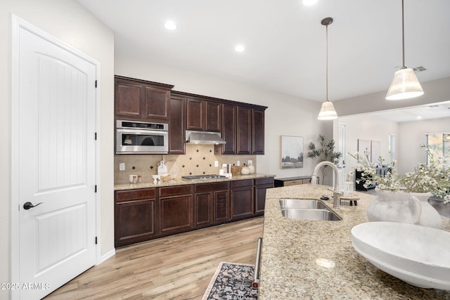 kitchen featuring light hardwood / wood-style flooring, pendant lighting, backsplash, appliances with stainless steel finishes, and sink