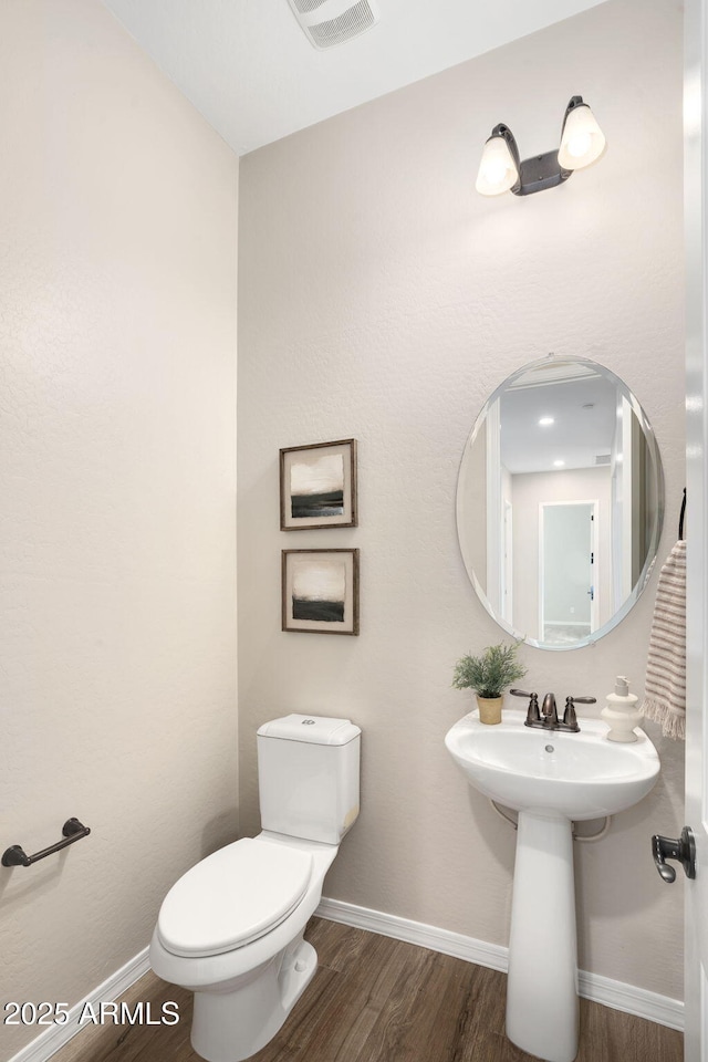 bathroom featuring toilet and wood-type flooring