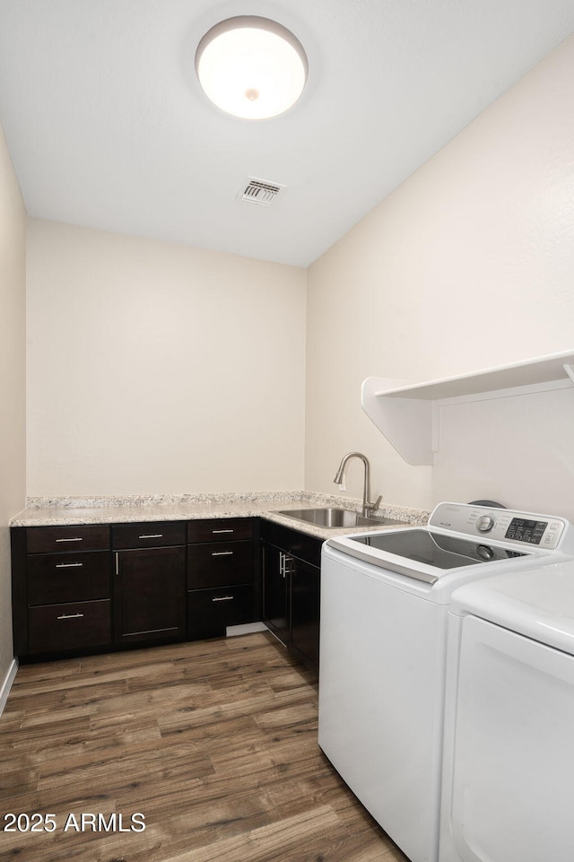 laundry area featuring sink, washing machine and dryer, cabinets, and dark hardwood / wood-style floors