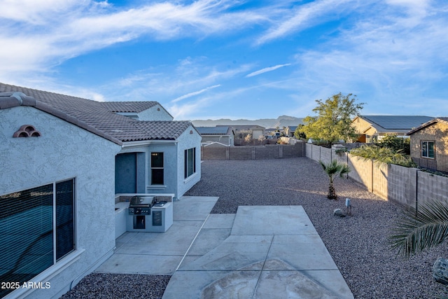 view of patio with exterior kitchen, a mountain view, and a grill