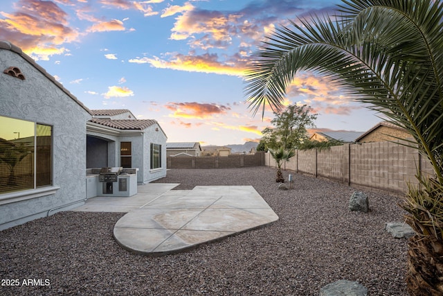 patio terrace at dusk featuring area for grilling and a grill