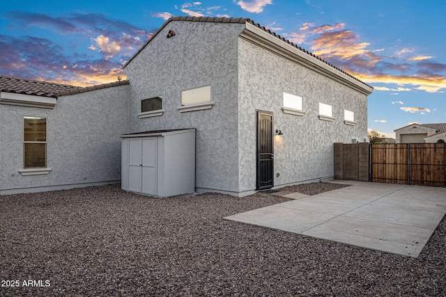 back house at dusk featuring a patio area