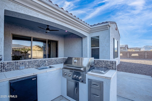 view of patio / terrace with an outdoor kitchen, sink, ceiling fan, and area for grilling