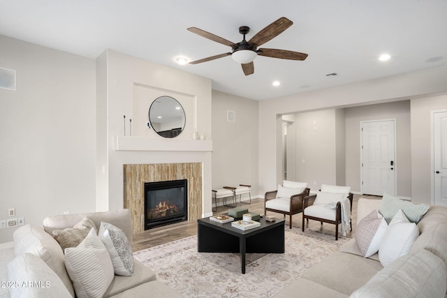 living room featuring a fireplace, ceiling fan, and light hardwood / wood-style floors