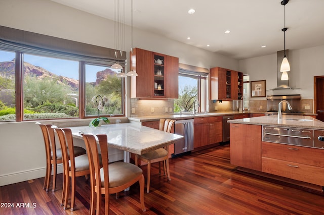 kitchen featuring tasteful backsplash, brown cabinetry, dishwasher, light stone counters, and exhaust hood