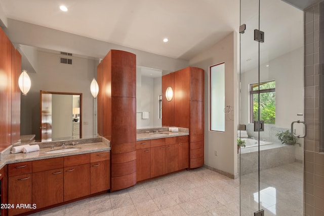 full bath with two vanities, a sink, visible vents, and a garden tub