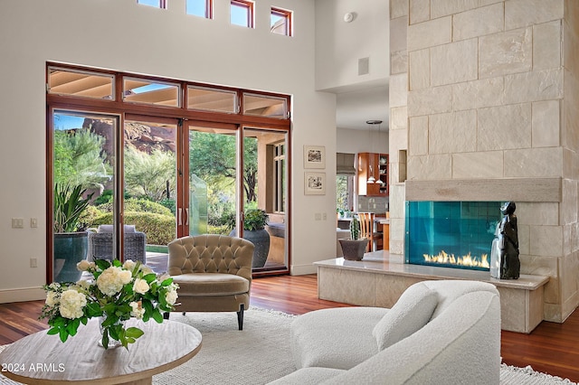 living area with baseboards, a tiled fireplace, visible vents, and wood finished floors