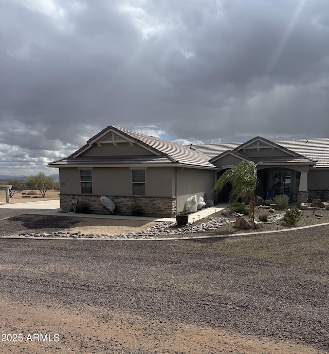 view of front of property with stone siding, a tile roof, and stucco siding