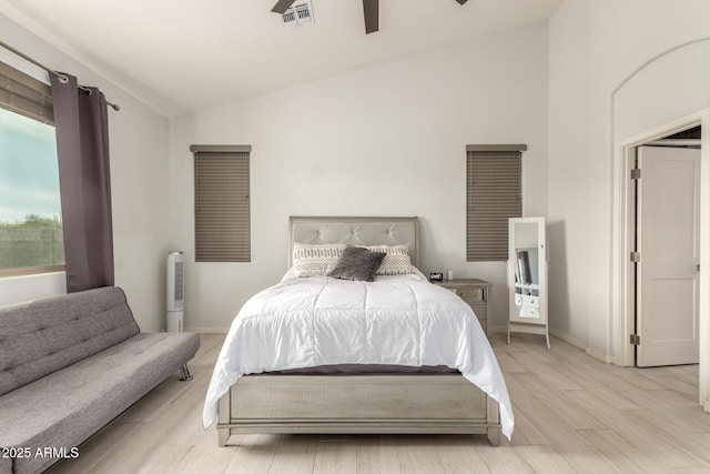 bedroom featuring lofted ceiling, baseboards, visible vents, and light wood-style floors