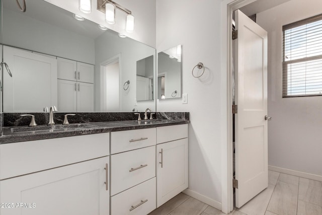 bathroom featuring double vanity, a sink, and baseboards