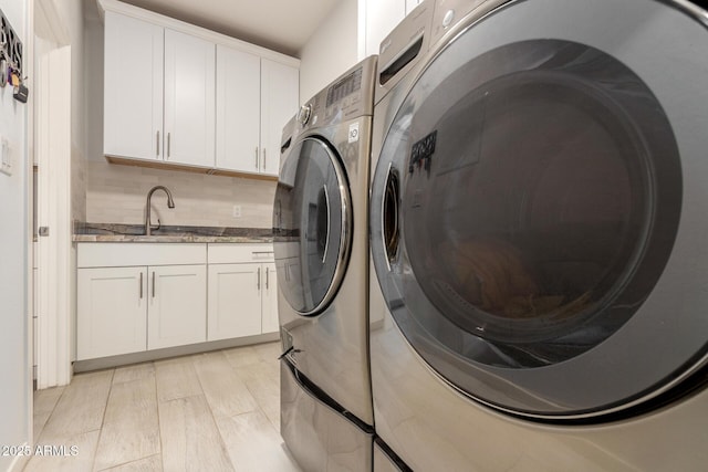 laundry room featuring light wood-type flooring, washer and dryer, cabinet space, and a sink