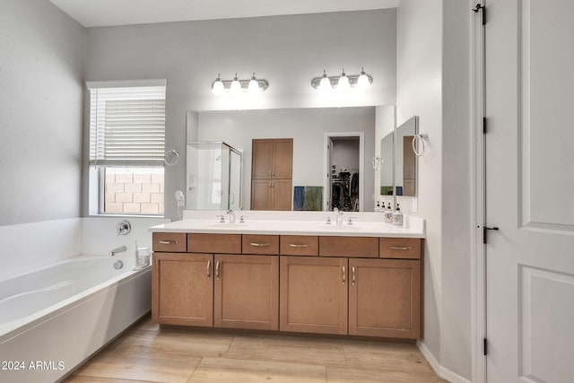 bathroom with a stall shower, double vanity, a sink, and a bath