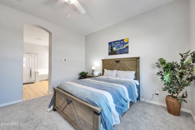 carpeted bedroom featuring connected bathroom, arched walkways, ceiling fan, and baseboards