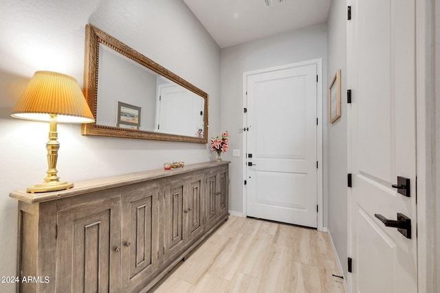 doorway with light wood finished floors, baseboards, and visible vents